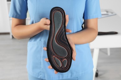 Female orthopedist showing insole in hospital, closeup