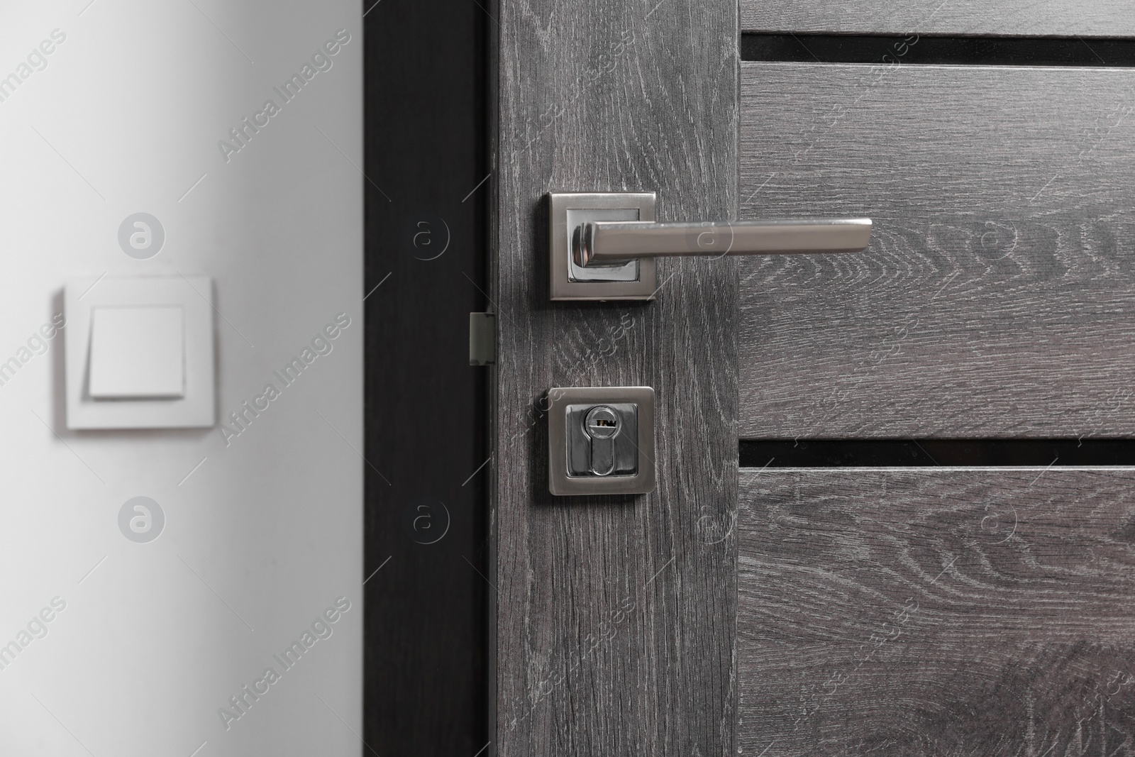 Photo of Open wooden door with metal handle indoors, closeup
