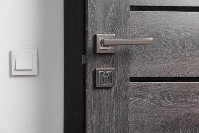 Open wooden door with metal handle indoors, closeup