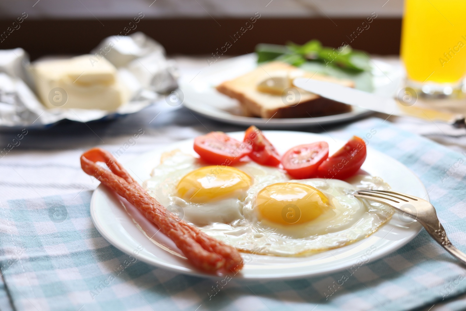 Photo of Tasty fried eggs with smoked sausages and tomatoes on table, closeup