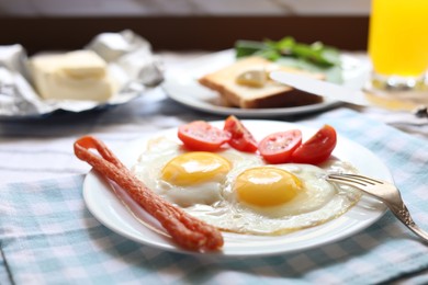 Tasty fried eggs with smoked sausages and tomatoes on table, closeup