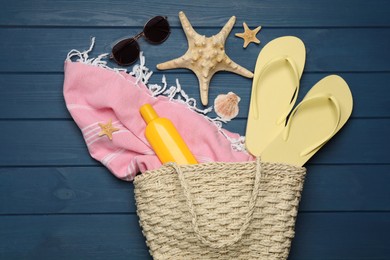 Stylish bag and beach accessories on blue wooden background, flat lay