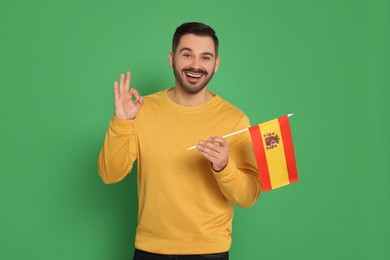 Photo of Man with flag of Spain showing ok gesture on green background