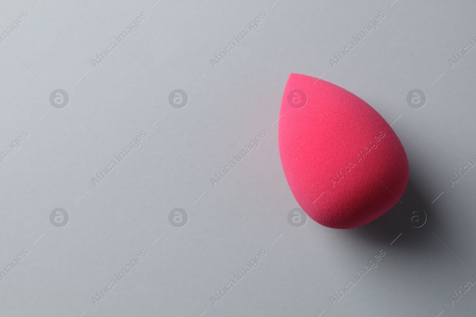 Photo of One pink makeup sponge on grey background, top view. Space for text