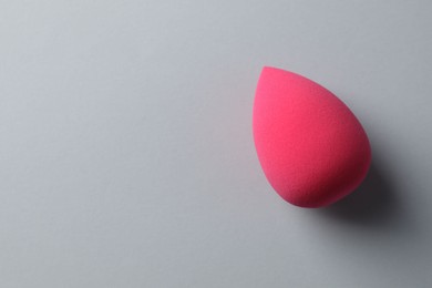 Photo of One pink makeup sponge on grey background, top view. Space for text