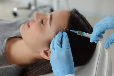 Trichologist giving injection to patient in clinic, closeup