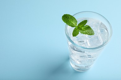 Photo of Glass of soda water with ice and mint on turquoise background. Space for text