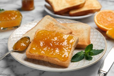 Photo of Delicious toasts with jam and mint on white marble table, closeup