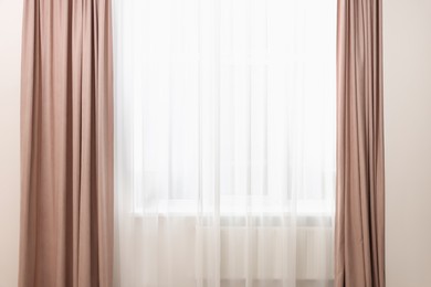 Photo of Elegant window curtains and white tulle indoors. Interior design