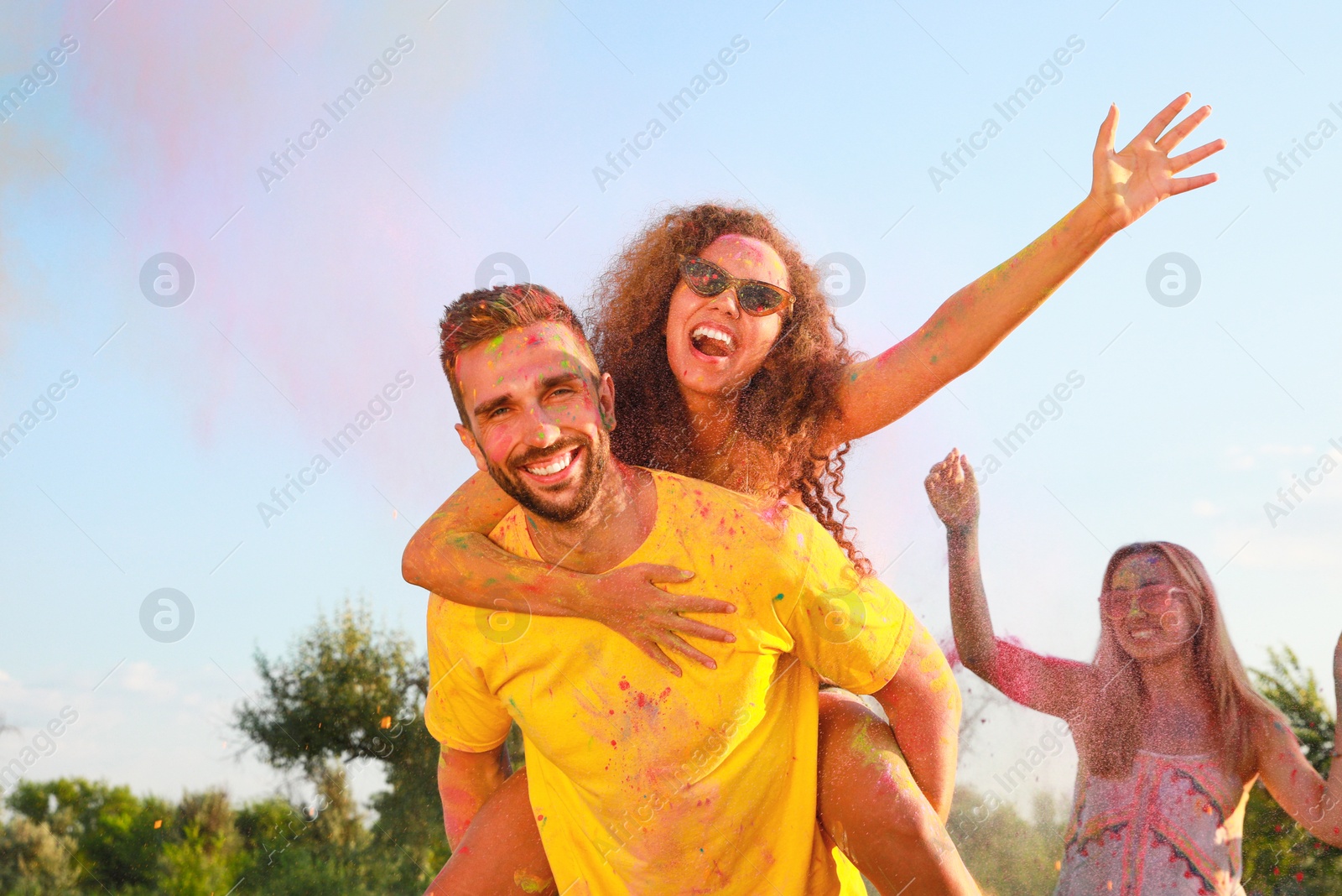 Photo of Happy couple covered with colorful powder dyes outdoors. Holi festival celebration