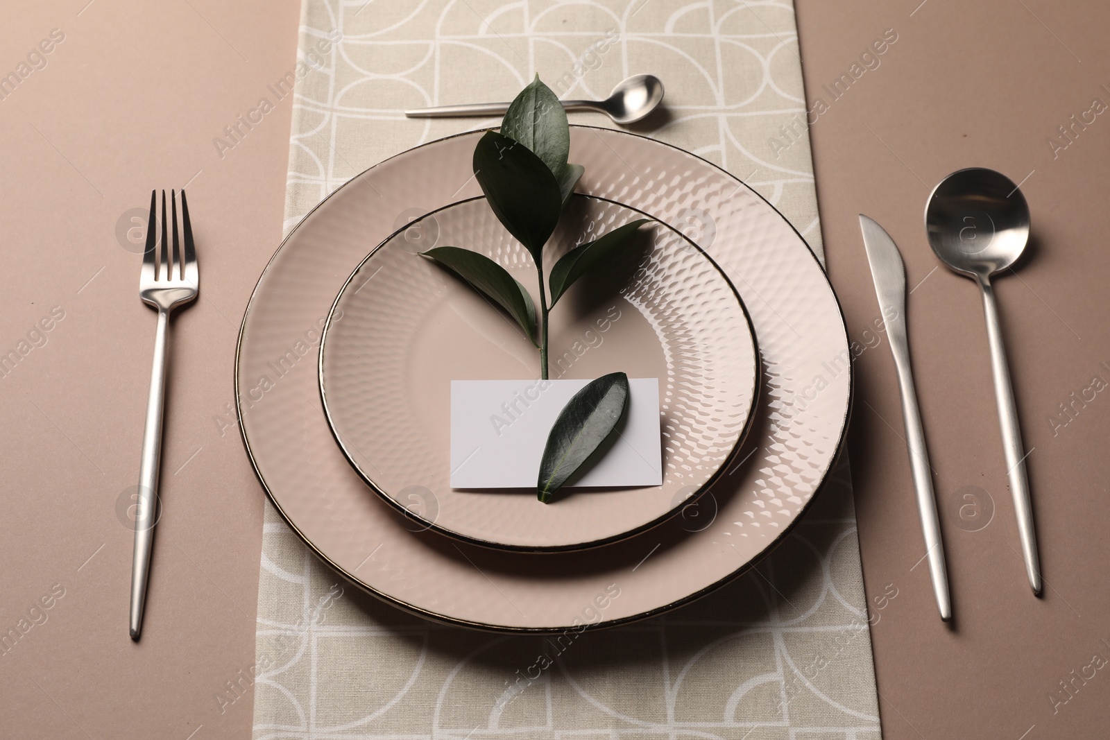 Photo of Stylish table setting. Plates, cutlery, blank card and green twig on beige background