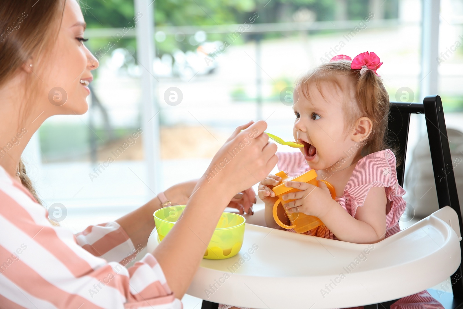 Photo of Caring mother feeding her cute little baby with healthy food at home