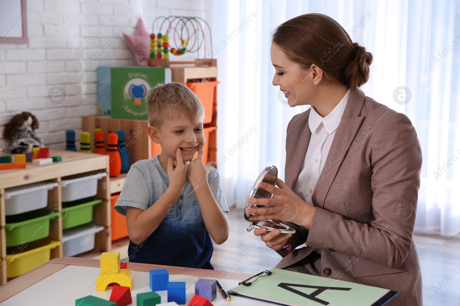 Photo of Speech therapist working with little boy in office