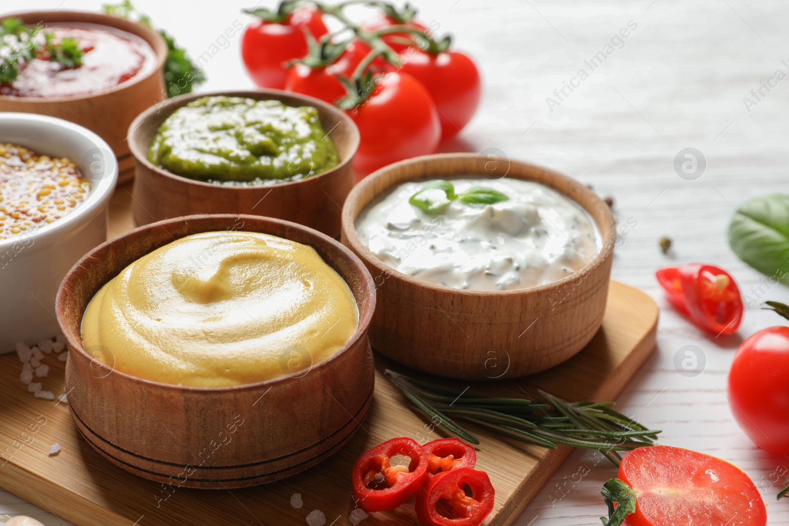 Photo of Board with bowls of different sauces on table