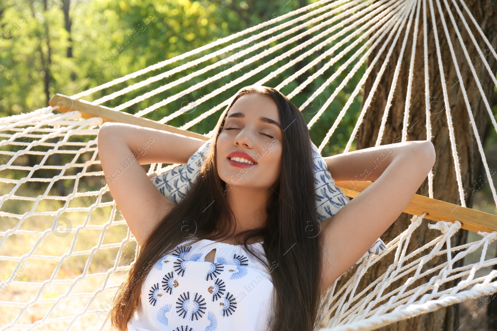 Photo of Young woman resting in comfortable hammock at green garden