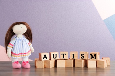 Doll and cubes with word "Autism" on table