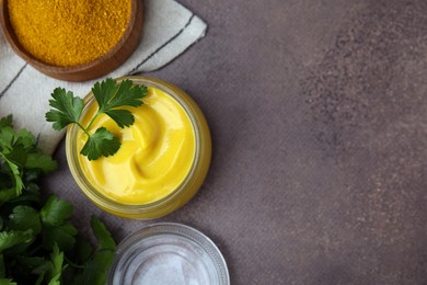 Tasty curry sauce, powder and parsley on brown table, flat lay. Space for text