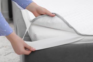 Photo of Woman putting cover on mattress indoors, closeup