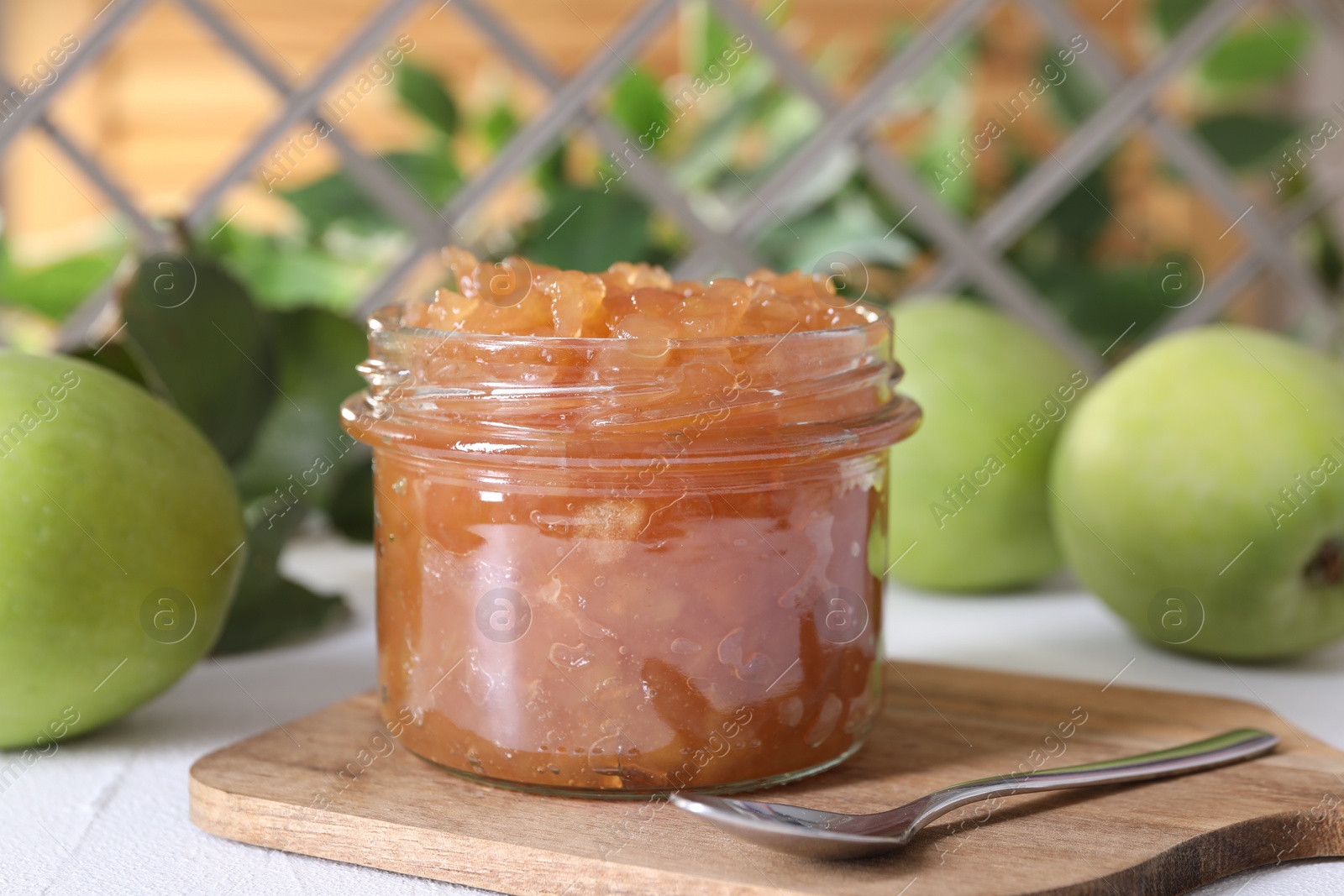 Photo of Glass jar of delicious apple jam and fresh fruits on white table