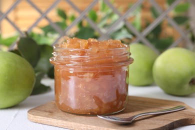 Photo of Glass jar of delicious apple jam and fresh fruits on white table