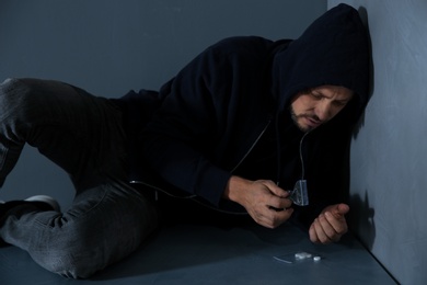 Photo of Young addicted man with drugs lying on floor