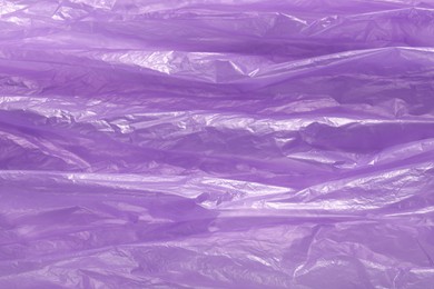 Photo of Crumpled purple plastic bag as background, top view