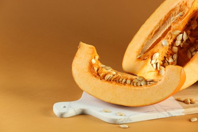 Photo of Cut fresh ripe pumpkin on orange background. Space for text
