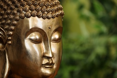 Photo of Buddha statue against blurred green background, closeup. Space for text