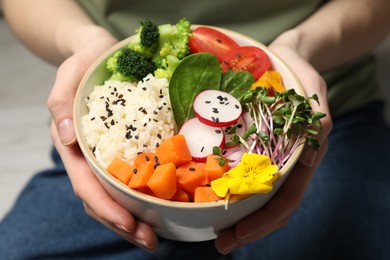 Photo of Woman holding bowl with different vegetables and rice, closeup. Vegan diet