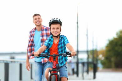 Photo of Dad teaching son to ride bicycle outdoors