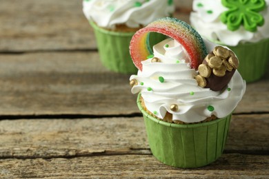Photo of St. Patrick's day party. Tasty festively decorated cupcakes on wooden table, closeup. Space for text