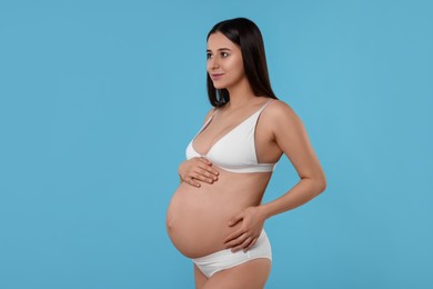 Photo of Beautiful pregnant woman in stylish comfortable underwear on light blue background