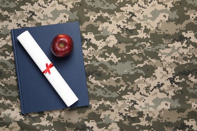 Photo of Notebook, apple and diploma on camouflage background, top view with space for text. Military education