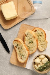 Photo of Tasty baguette with garlic and dill served on light grey table, flat lay