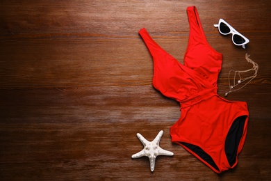 Photo of Beautiful swimsuit and sunglasses on wooden background, top view