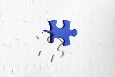 Photo of Blank white puzzle with separated piece on blue background, top view