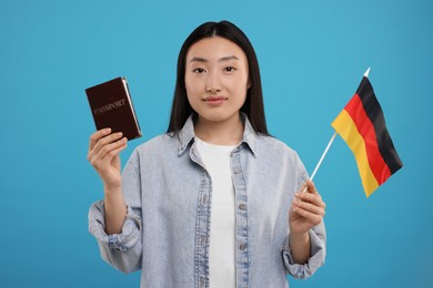 Photo of Immigration to Germany. Woman with passport and flag on light blue background