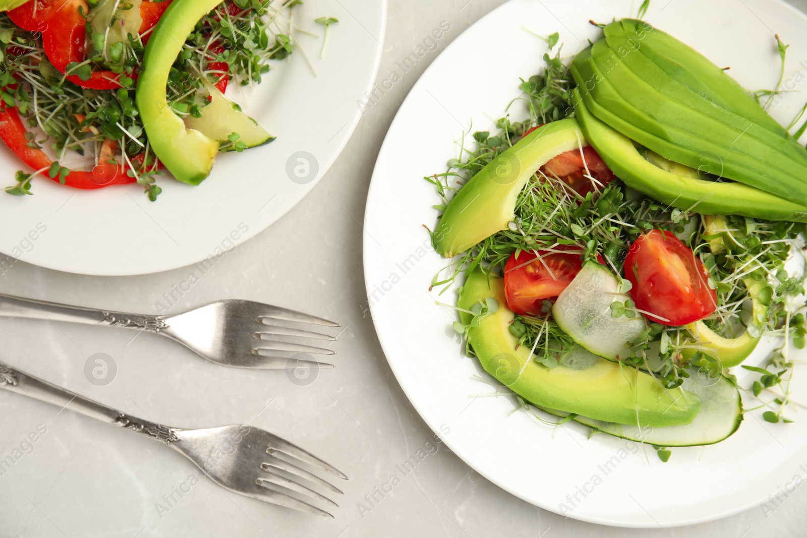 Photo of Delicious vegetable salads with avocado and microgreen served on light table, flat lay