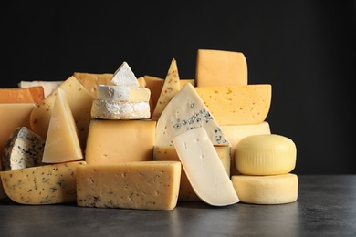 Photo of Different types of delicious cheese on table against black background