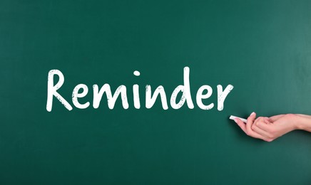 Image of Woman writing word Reminder on chalkboard, closeup