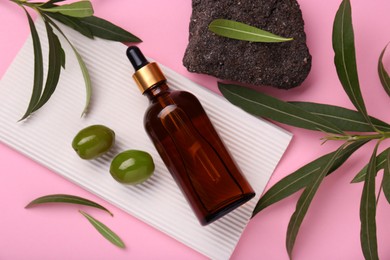 Photo of Cosmetic products with olive essential oil, stone and leaves on pink background, flat lay