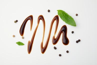 Photo of Organic balsamic vinegar, peppercorns and basil leaves on white background, flat lay