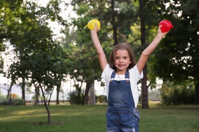 Photo of Cute little girl holding water bombs in park