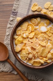 Photo of Tasty cornflakes with milk in bowl served on wooden table, flat lay