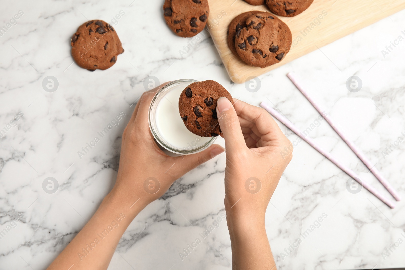 Photo of Woman with tasty chocolate chip cookies and milk on light background, closeup