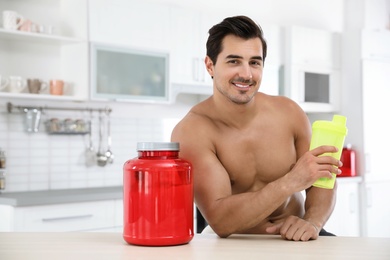 Photo of Young shirtless athletic man with protein shake powder in kitchen, space for text