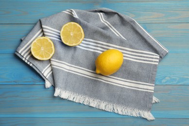 Photo of Striped kitchen towel and lemons on light blue wooden table, flat lay