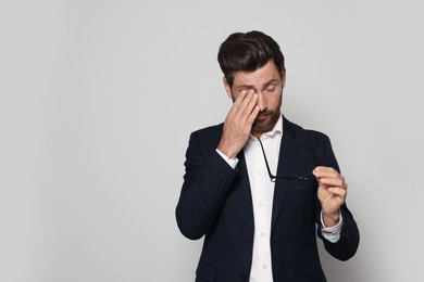 Photo of Man suffering from eyestrain on light grey background. Space for text