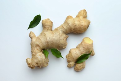 Fresh ginger with green leaves on white background, flat lay