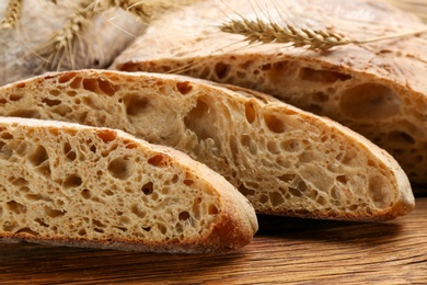 Photo of Tasty freshly baked bread on wooden table, closeup